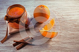 Orange jam in glass jar and oranges on wooden table, top view