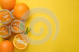 Orange jam in a glass jar on a yellow background. With empty space for writing