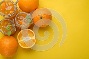 Orange jam in a glass jar on a yellow background. With empty space for writing