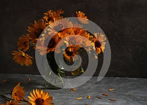 Orange Jerusalem artichoke flowers in a vase on a dark background