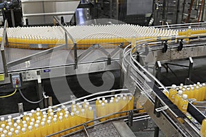 Orange juice bottles on conveyor belt in bottling plant