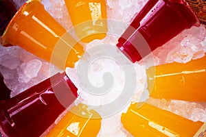 Orange juice and colorful sweet water on ice crystals