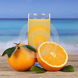 Orange juice drink and oranges on the beach and sea