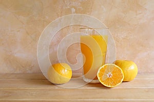 Orange juice in a glass and fresh fruit on table