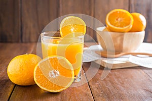 Orange juice in glass, fresh fruits on wooden background