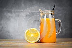 Orange juice in the glass jar and fresh orange fruit slice on wooden table - Still life glass juice on dark background