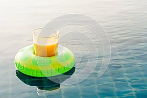 Orange juice glass with swim ring at outdoor swimming pool