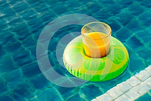 Orange juice glass with swim ring at outdoor swimming pool