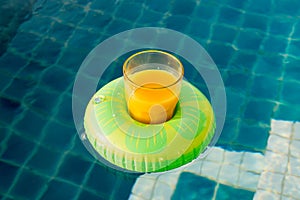 Orange juice glass with swim ring at outdoor swimming pool