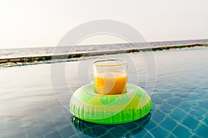 Orange juice glass with swim ring at outdoor swimming pool