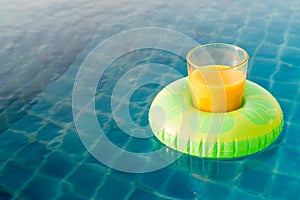 Orange juice glass with swim ring at outdoor swimming pool