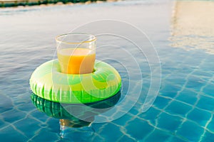 Orange juice glass with swim ring at outdoor swimming pool
