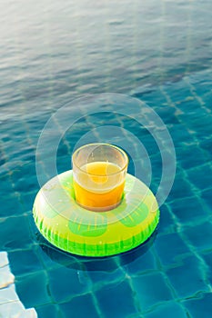 Orange juice glass with swim ring at outdoor swimming pool