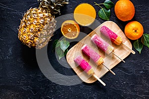Orange juice, oranges, mandarins, pineapple and citrus ice cream on wooden table background top view copyspace