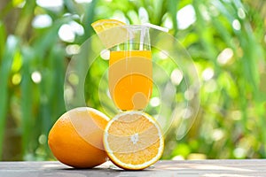Orange juice with piece orange fruit on glass with nature green summer background