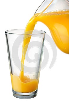 Orange juice is poured from pitcher into the glass