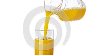 Orange juice pouring from pitcher into glass isolated on white background