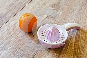 Orange and juice reamer on wooden table
