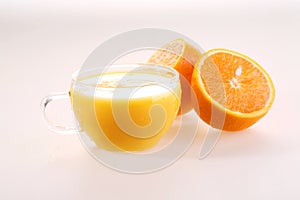 Orange juice in a transparent cup and halves of a juicy ripe ora