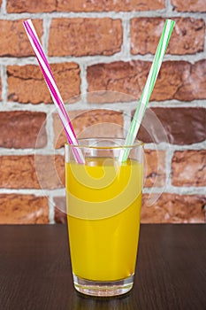 Orange juice Two straws Vitamins Health concept wooden background and brick wall