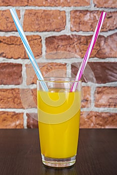 Orange juice Two straws Vitamins Health concept wooden background and brick wall