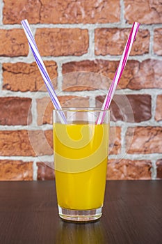 Orange juice Two straws Vitamins Health concept wooden background and brick wall