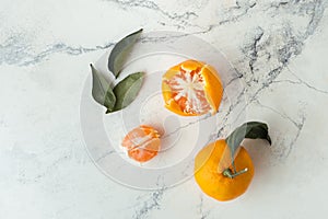 Orange juicy tangerine slices and peeled mandarines scattered on the white marble background. Flat lay. Copy space. Fresh summer