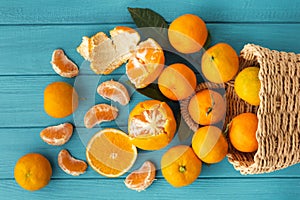 Orange juicy tangerine slices and peeled mandarines scattered on the wooden turquoise background. Flat lay. Copy space. Fresh
