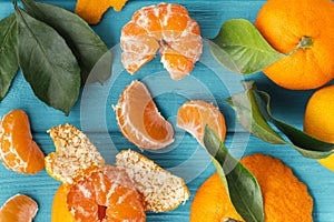 Orange juicy tangerine slices and peeled mandarines scattered on the wooden turquoise background. Flat lay. Fresh summer vitamin