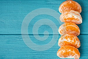 Orange juicy tangerine slices on the wooden turquoise background. Flat lay. Copy space. Fresh summer vitamin rich fruits