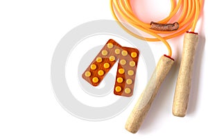 Orange jump rope with blisters of pills on white background. Healthy living concept