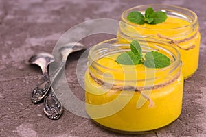 Orange kurd or dessert in low jars. Orange summer, refreshing dessert on a gray background. photo