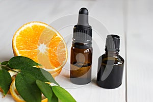 Orange, leaves and brown bottles with essential oil on wooden table