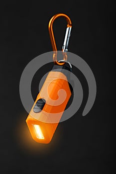 Orange led Flashlight with a carabiner on a black background. LED lights in flight