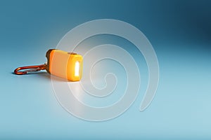 Orange led Flashlight with a carabiner on a blue background. LED lights in flight