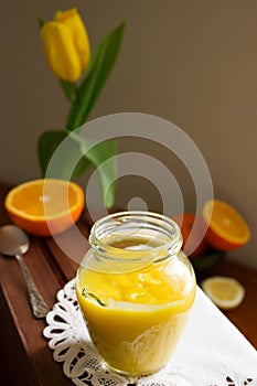 Orange-lemon curd and slices of oranges and lemons on a wooden surface. Rustic style.