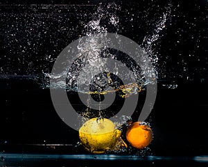 An orange and a lemon dropped in water