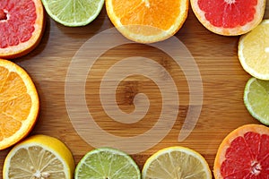 Orange, lemon, grapefruit and lime half slices on wooden board with copy space. Mix of sliced colorful citrus fruits top view.