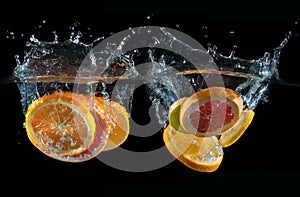 Orange, lemon, grapefruit and lime splashing into water
