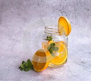 Orange-lemon lemonade with mint in a glass that stands on the table