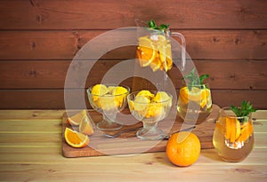 Orange lemonade,  orange ice cream and fresh oranges on cutting board on rustic wooden table. Selective focus