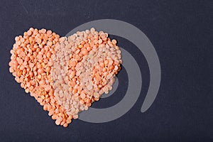 Orange lentils in a heart shape on a black background