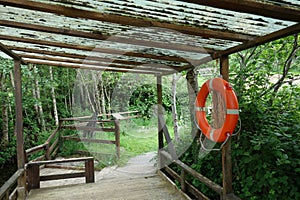 orange life belt at a wooden pole . rescue tire at the peer . rescue ring next to the water to safe drowning people concept image
