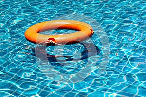 Orange life buoy floating on the surface of blue water