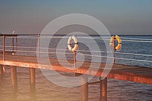 Orange life buoy hanging on an old pier by the sea