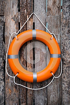 Orange life buoy hanging on wooden wall