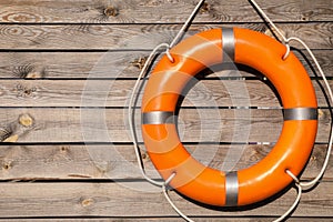 Orange life buoy hanging on wooden wall, space for text