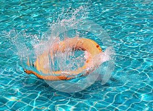 Orange life buoy splash water in the blue swimming pool