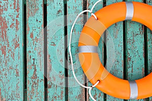 Orange life buoy on turquoise wooden background, top view. Space for text