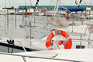 Orange life buoy on white yacht berthed at marina